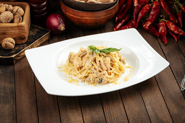 Carbonara paste with smoked chicken and mushrooms on wooden background