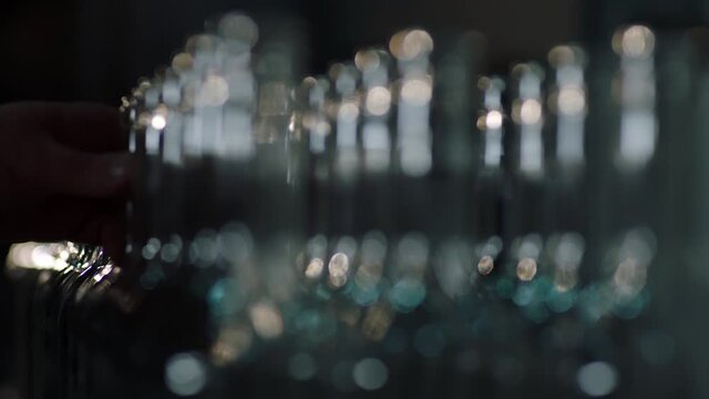 Many empty bottles for alcohol drinks on the table . Sorting bottles in wine factory . Close up view of row of red wine bottles . Shot on ARRI ALEXA Cinema Camera in slow motion .