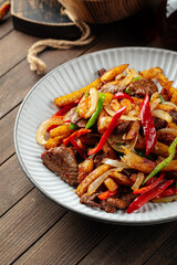 Beef meat roast with potato and pepper on a wooden background