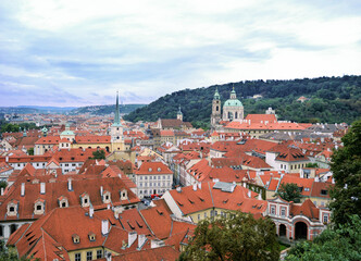 Fototapeta na wymiar Red roofs of houses of the old part of Prague on a background of green hills.