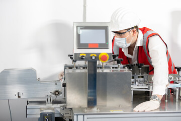 engineer man or factory worker wearing face mask for protect virus, using the machine in factory