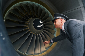 Serious young aviator inspecting the turbofan engine