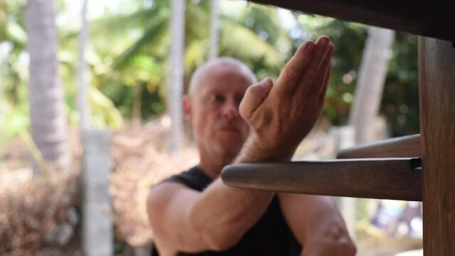 Kung fu master, sensei, teacher, adult man hones his skills with the simulator. The man is practicing kung fu strikes. close-up, portrait of sport adult man