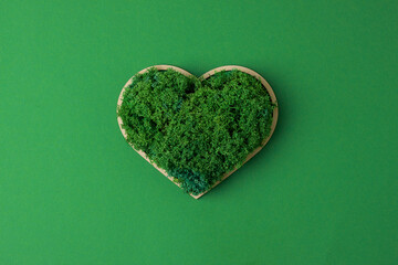 Cosmetic background with a wooden heart and moss on green. Flat lay, copy space