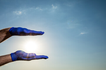 Male hands in medical blue gloves. COVID-19. Coronavirus. Cloudy sky background.