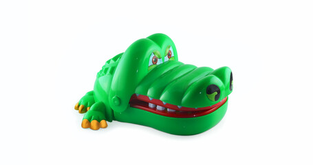 Green toy crocodile biting finger on white isolated background