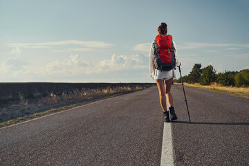 Obraz premium Back view of tourist moving on asphalt road