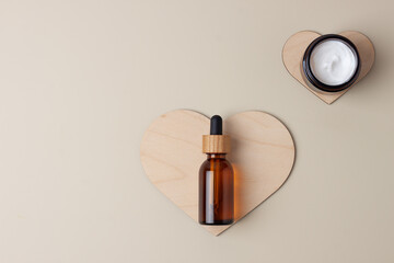 Cosmetic skin care products with a wooden heart on pastel beige background. Flat lay, copy space