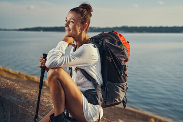 Travelling woman dreaming while sitting on stone barrier