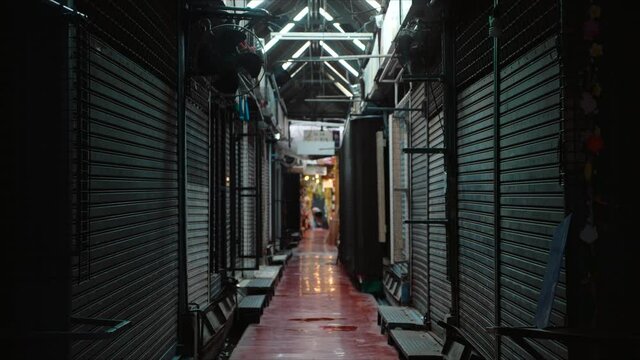 Empty shop store fronts closed due Coronavirus Pandemic lockdown, Metal roller shutter door of store in flea market is closed and locked in dark light, Economic downturn.