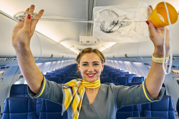 Friendly air hostess demonstrating a breathing apparatus