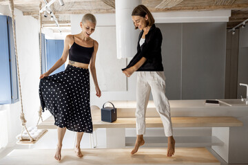 Stylish female couple dancing together having fun during a party in the modern studio apartment. Homosexual relations and happy leisure time at home