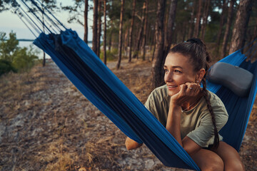 Female daydreaming while lying on hammock in the woods
