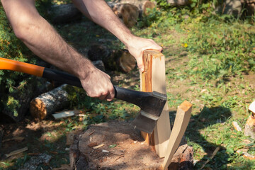 A closeup shot of man hands with a log and an axe by summer day