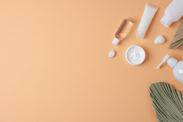 Cosmetic skin care products with palm leaf on pastel beige background. Flat lay, copy space