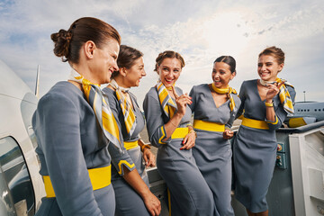 Joyful stewardesses standing on the boarding stairs during the conversation