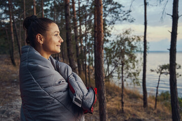 Female wrapping herself in blanket in forest