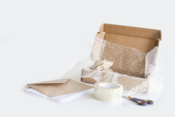 Tape, box, bubble wrap, scissors, paper envelope. Product packaging concept.