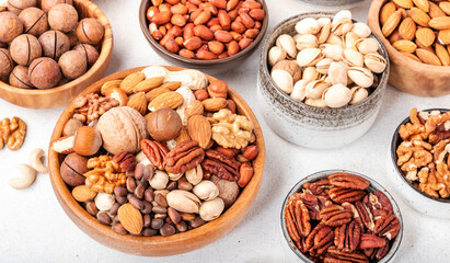 Nut mix in bowl. Almonds, hazelnuts, walnuts and other. Healthy food snack mix on white table, top view, copy space