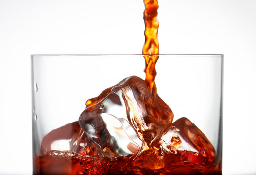 Close de bebida vermelha caindo sobre cubos de gelo