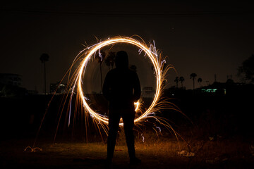 Man creating rotating and swirling sparks in a dark place