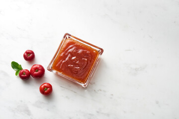 Geléia de Acerola em mesa com frutos de acerola ao lado
