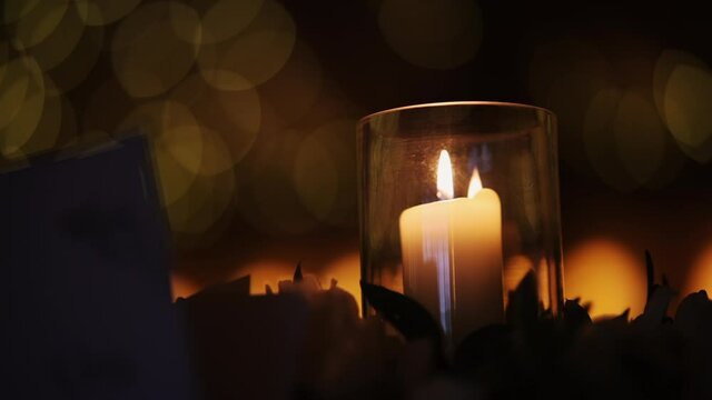 A handheld shot of warm candlelight in a glass jar with bokeh