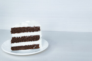 The slice of chocolate sponge cake with butter cream is located on the left