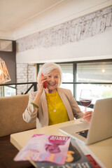 Elegant senior woman sitting with a smartphone in hands