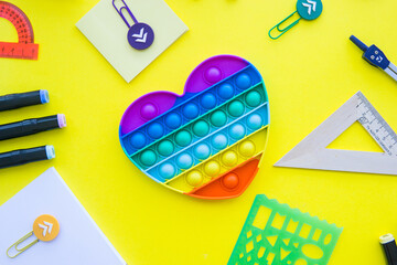 Close up of stationery and silicone toy popit. Flat lay composition. Yellow background. Space for...