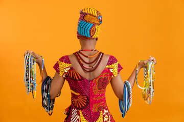 The African woman is dressed in national clothes and turned her back to the camera. She has a lot...