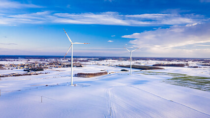 Wind turbine and snowy field at sunrise in winter