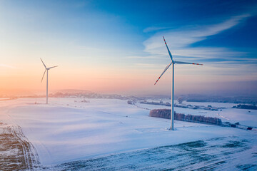 Wind turbine on snowy field. Aerial view of winter nature