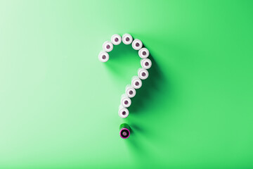 AA batteries in the form of a question mark on a green background with free space