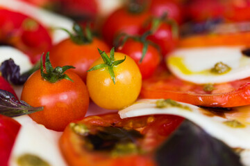 Italian caprese salad with mozzarella cheese and tomatoes garnished with cherry tomatoes, pesto sauce, balsamic vinegar and basil leaves 