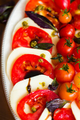 Italian caprese salad with mozzarella cheese and tomatoes garnished with cherry tomatoes, pesto sauce, balsamic vinegar and basil leaves 