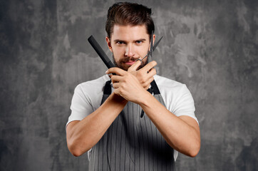 male hairdresser in an apron with a comb in his hands and scissors