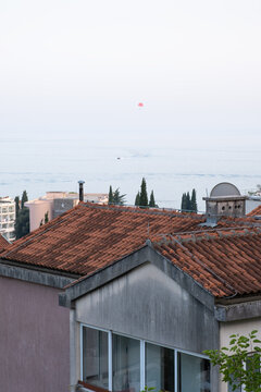 View of a distant parasailer flying over the see and rooftops of Becici, Montenegro against a colorful sky