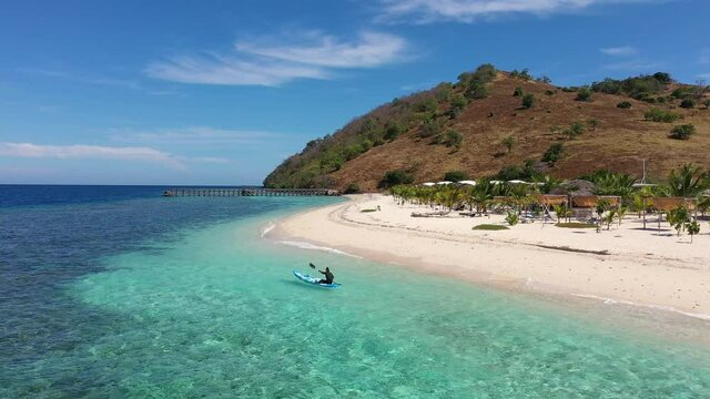 Aerial drone footage of kayak on the turquoise waters of an idyllic island off the coast of Flores in Labuan Bajo, Indonesia. Shot with a backward motion. 