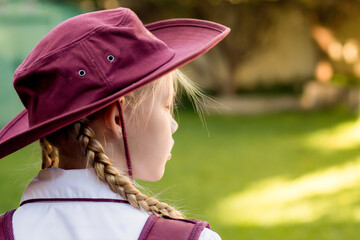 A girl wearing school uniform, white shirt, maroon backpack and a hat Back to school. Return to classrooms after COVID-19 outbreak in Australia