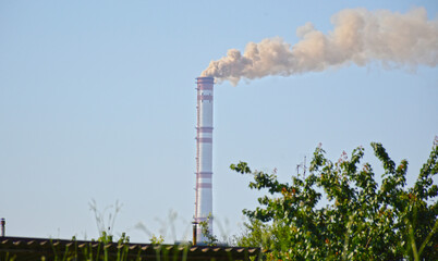 problems of environmental pollution and ecology. dark gray pungent smoke comes from a chimney of an industrial plant or thermal power plant against the background of the sky.
