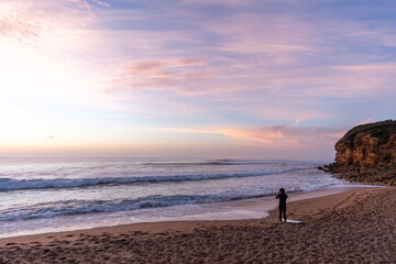 Sunrise at Bells Beach, Victoria, Australia with surfer looking out at the waves