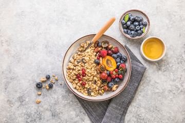 Oat granola with fruits in bowl on concrete background. berry and blueberries with crunchy oat honey granola, healthy breakfast cereals