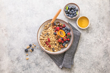 Oat granola with fruits in bowl on concrete background. berry and blueberries with crunchy oat honey granola, healthy breakfast cereals