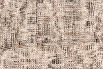 Natural burlap with large cells. The texture of a coarse woven fabric with mesh and fibers.