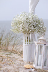 Bohemian wedding bouquets , seashells and burning candle on sand by sea ​​coast