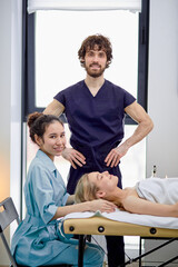 Two caucasian masseurs practice massaging on female client face and head, male and female masseur...