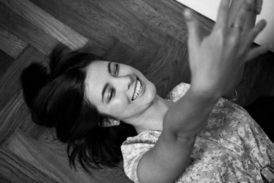 Monochrome portrait of a young smiling woman lying on the floor