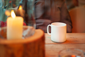 A cup of tea  on wood table and blurred candles on background.