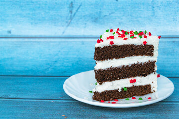 A piece of chocolate cake with a layer of butter cream located on the right. Blue background. Close-up